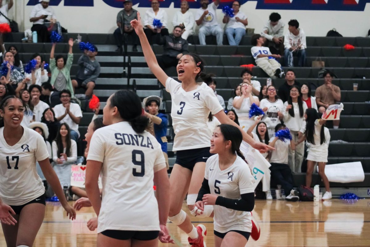 JUMPING WITH JOY: Sophomore Brandy Nguyen leaps into the air in celebration after girls Varsity volleyball scores a point against Whitney.