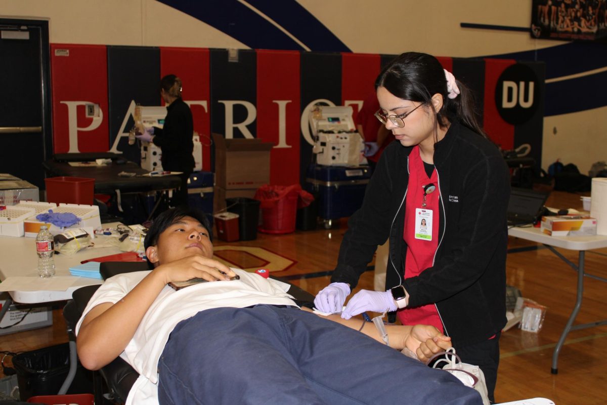 Donating for a Cause: American Red Cross employee Milenia Hernandez draws blood from Senior Matthew Kim at the blood drive. 