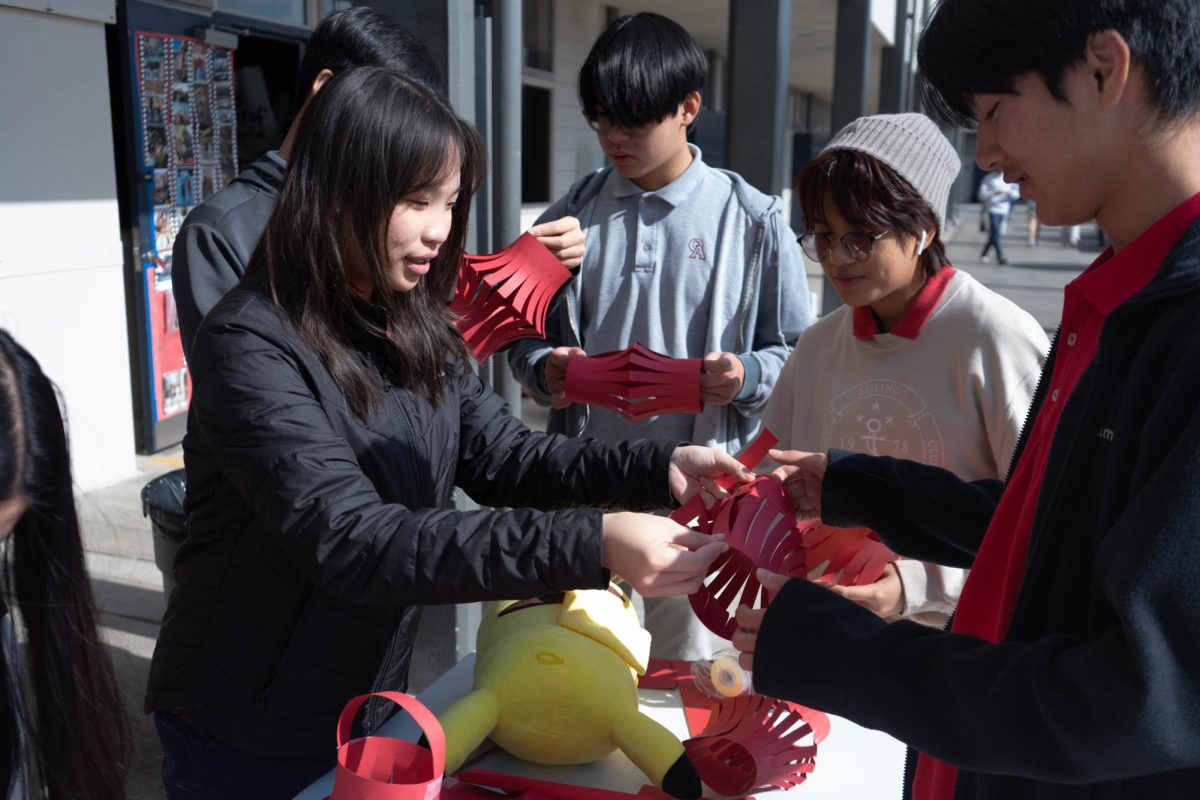 TRADITIONAL CRAFTS: Phoebe Lin (11) hands a hand-crafted paper lantern, red for protection and good fortune, to Jaden Zhang (11).